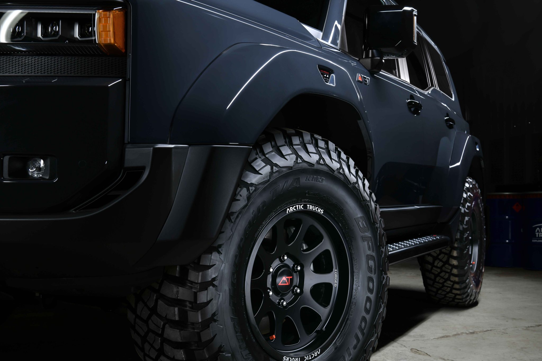 Close-up of a rugged black SUV highlighting its large, textured tires and sleek body. The image conveys power and off-road capability.