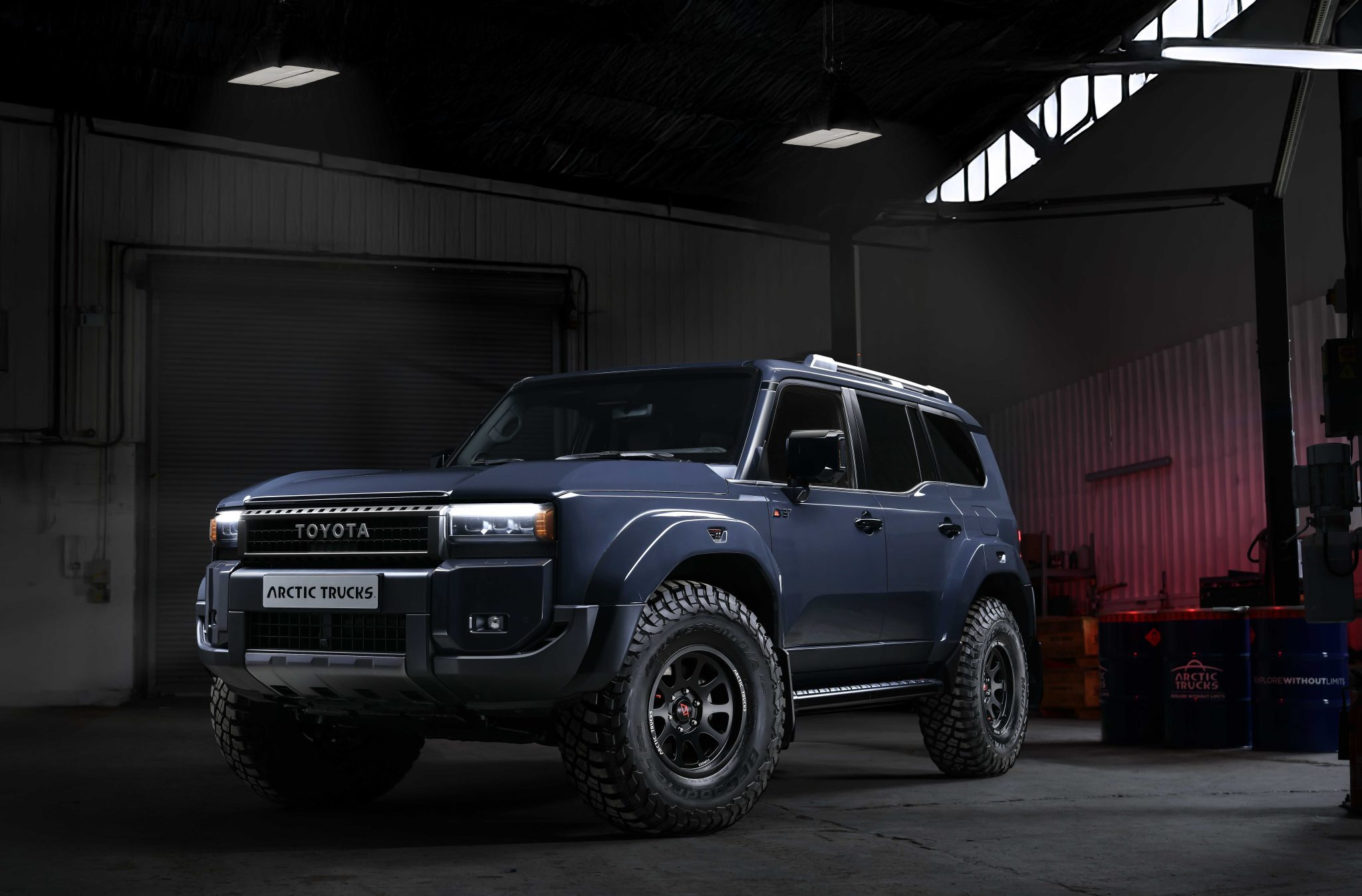 Dark garage with a rugged blue Toyota SUV, "Arctic Trucks" on the front. Illuminated by overhead lights, the vehicle exudes a powerful, adventurous vibe.